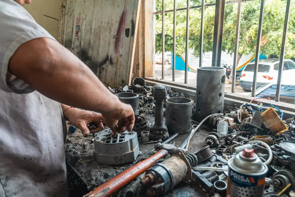 Seorang pria sedang membongkar karburator motor di meja kerja bengkel rumahan dengan peralatan sederhana